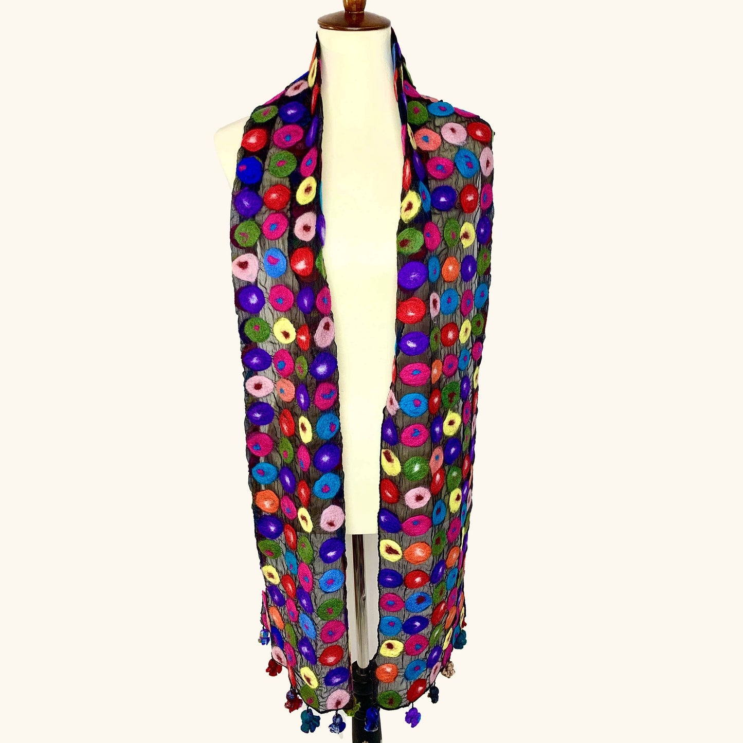 Colorful patterned hand made scarf on a mannequin against a white background, draped view
